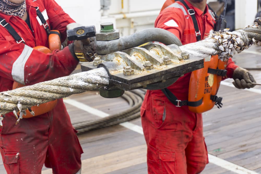 Marine crew doing anchor handling activities with selective focus.