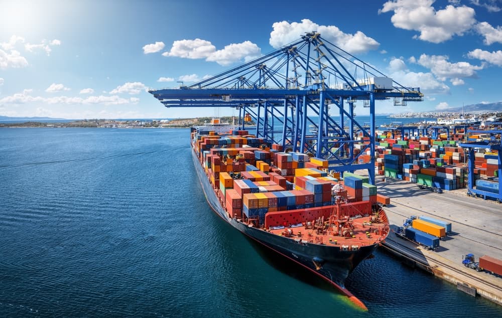 A large container cargo vessel is beeing loaded and unloaded by large cranes in a commercial dock