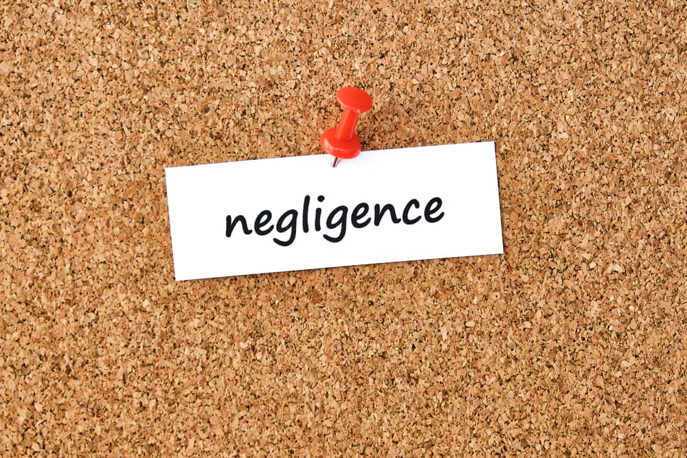 Negligence Word written on a piece of paper or note, cork board background.